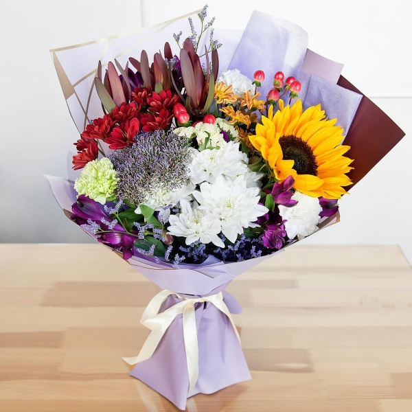 Green carnation - 2, Baltica White Spray Chrysanthemum - 2, Alstromeria lilac, purple - 5, Sunflower - 1, Bacardi Yellow Spray Chrysanthemum - 2, Bacardi Red Spray Chrysanthemum - 1, Carnation white, cream - 3, Hypericum, Limonium (1 pc.), Leukodendron, Wrapping Paper, Trachelium